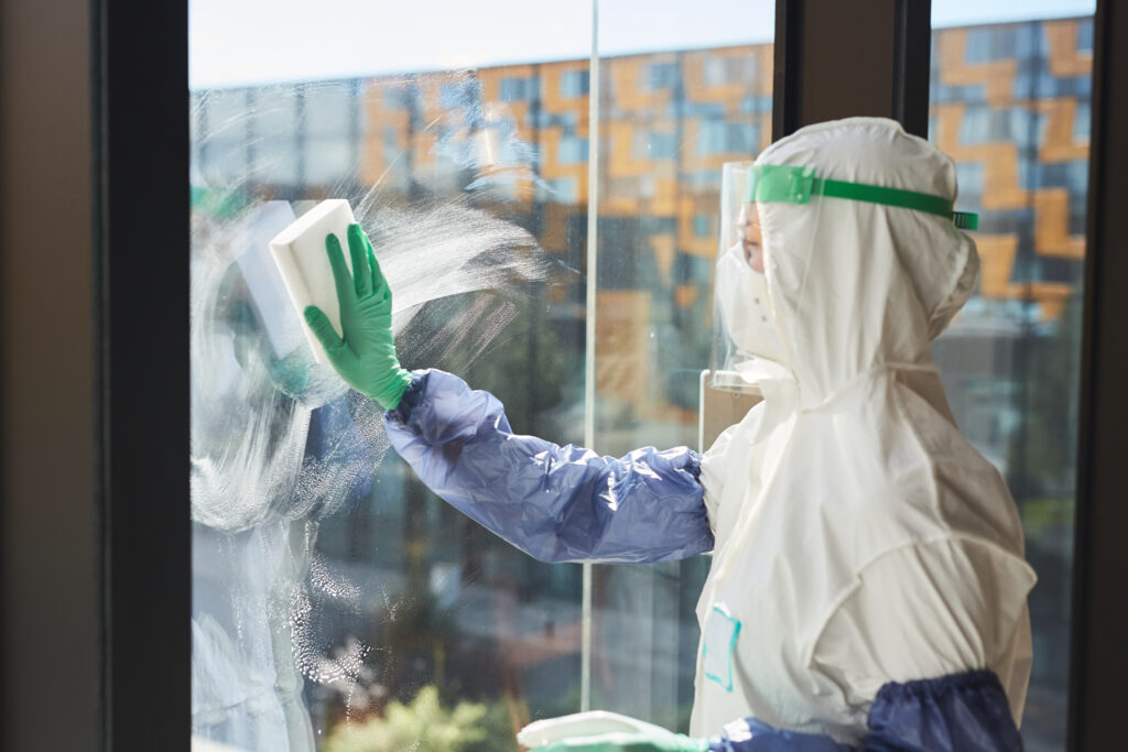 Profissional de limpeza a limpar janelas com detergente